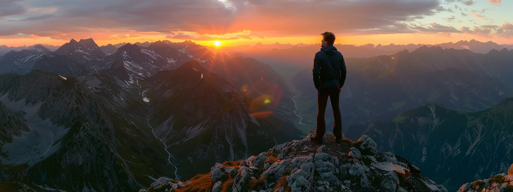 a young entrepreneur confidently standing at the top of a mountain peak, overlooking a breathtaking sunset with the world at his feet.